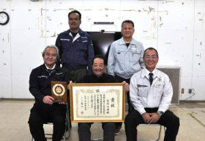 特別賞の賞状を手にする宮国さん(前列中央)。同左は賞状を伝達した仲村理事長、同右は下地本部長ら関係者=20日、JAおきなわ宮古地区本部