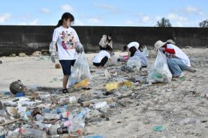 海岸の漂着ごみを集める学生たち＝28日、高野漁港横のビーチ