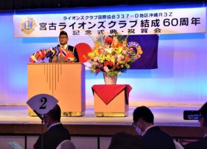 宮古ライオンズクラブ結成60周年記念式典であいさつをする富山会長=25日、ホテルアトールエメラルド宮古島