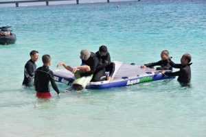 水中から溺れた選手を想定し救助する参加者ら＝４日、下地与那覇の前浜ビーチ