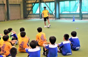 子どもたちにサッカーの基本動作を説明する福田さん＝30日、市前福多目的屋内運動場
