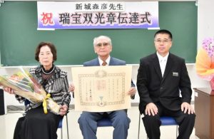 叙勲の伝達を受けた新城さん（中央）、左は妻の千恵子さん、右は伝達した平良所長＝21日、県宮古合同庁舎