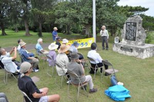 仲宗根共同代表（右奥）のあいさつを聞く参加者＝3日、カママ嶺公園