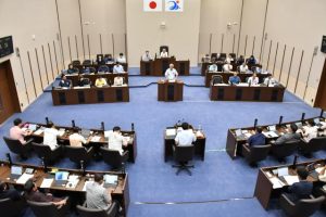 選挙公約である市民所得10％アップについて答弁する座喜味市長＝22日、市議会議場