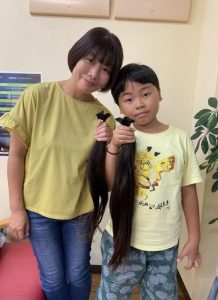 ヘアドネーションに寄付するため伸ばしていた髪を切った前田さん親子＝13日、市内の美容室（提供写真）