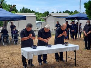 手を合わせる遺族会の参列者＝23日、村仲筋の慰霊の塔