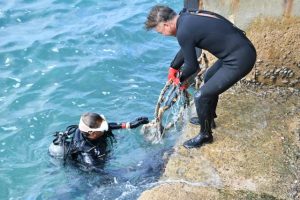 海中に落ちていたごみをダイバーらが引き上げた＝11日、来間港