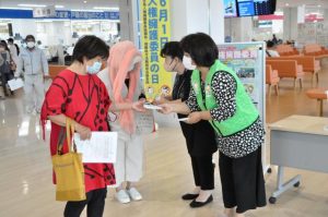 来庁した市民にウエットティッシュを手渡し人権擁護委員についてアピールする委員ら＝2日、市役所