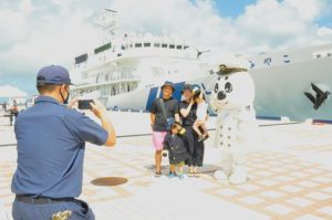 海上保安部の制服を着て記念写真を撮る家族連れ＝16日、平良港クルーズ岸壁