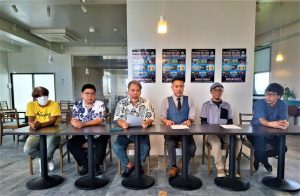 野津委員長（右から3人目）、砂川靖夫副委員長（同4人目）らがロックフェスティバルの開催日と出演アーティストを発表した＝18日、平良久貝