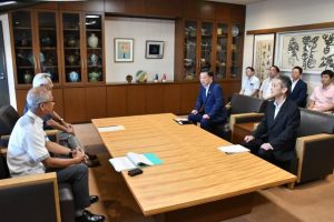 松野長官（奥）が来島し、座喜味市長らと国民保護について意見交換を行った＝23日、市役所