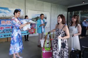 利用客100万人を達成し、ミス宮古らが到着客に記念品を手渡した＝8月30日、みやこ下地島空港ターミナル