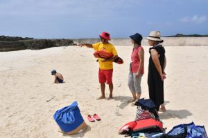 海水浴を楽しむ観光客らに注意喚起した＝10日、渡口の浜