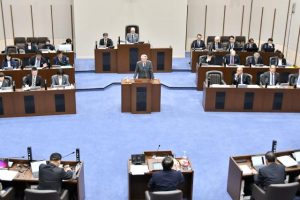 一般質問の初日で答弁する座喜味一幸市長（壇上）＝12日、市議会議場