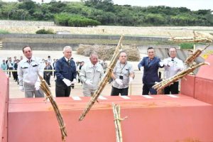 操業開始式でサトウキビを投げ入れる渡久山社長(左から3人目)ら関係者=13日、宮古製糖城辺工場