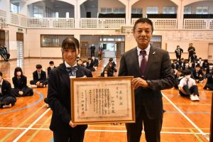 全国大会優秀賞に選ばれた下地さん（左）に岡田所長から表彰状が伝達された＝25日、城東中体育館