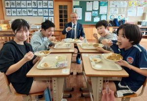 地元産食材の給食に笑顔の子供たちと嘉数副市長＝16日、上野小学校