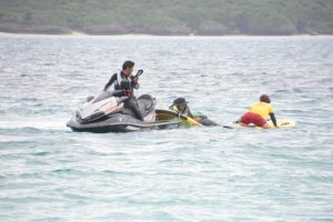 訓練で水中から溺れた選手役を救助する参加者ら＝28日、下地与那覇の前浜ビーチ