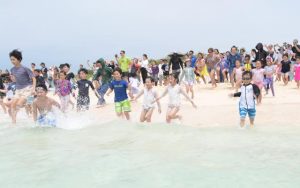 カウントダウン後、一斉に海に向かって走り出す子供たち＝３月31日、下地の与那覇前浜ビーチ