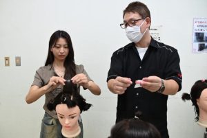 齋藤副校長（右）からパーマ巻きの指導を受ける椎屋さん＝２９日、働く女性の家ゆいみなぁ