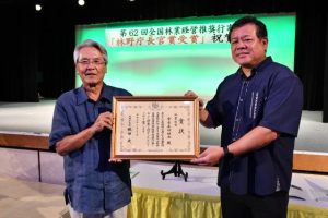 賞状を手にする座喜味市長（左）と佐和田勝彦常務理事＝３日、ホテルアトールエメラルド宮古島