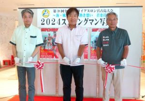 (左から)琉球新報社の普久原社長、JTAの野口社長、座喜味市長がテープカットを行い、「2024ストロングマン写真展」が開幕した=25日、那覇市の琉球新報社