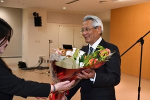 退任式であいさつ後に花束を受け取る座喜味市長=24日、市役所