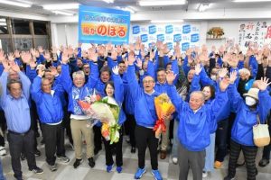 初当選を果たし支持者らと共に万歳する嘉数登氏(中央)=19日、平良西里の嘉数登氏選対本部