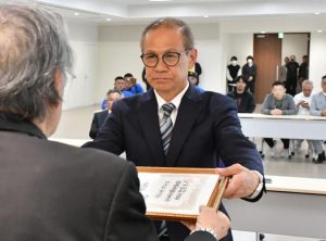 市選挙管理委員会の仲間委員長から当選証書を受け取る嘉数氏=22日、市役所