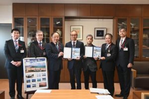 嘉数市長（中央）にオリジナルフレーム切手を贈った日本郵便の皆さん。右から３人目は写真協会の平良副会長 ＝30日、市役所