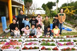 ボランティアサークル結代表の福島さん（後列右）から花が贈られた＝31日、伊良部こども園