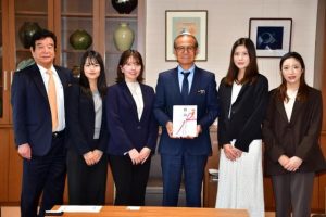 贈呈式には女子プロ４人が参加し髙橋会長（左）から嘉数市長に環境保全活動に役立ててと寄付金が贈呈された＝12日、市役所