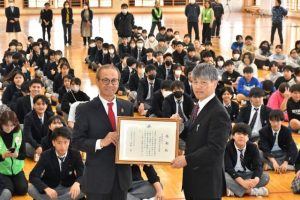 嘉数市長（手前左）から感謝状を受け取る佐久本校長（同右）＝６日、伊良部島小中体育館