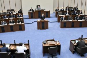 議案質疑でふるさと納税寄付金の実績について説明する久貝部長（壇上）＝28日、市議会