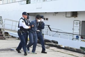 陸上でテロリストを確保し、パトカーへ連行する宮古島署の署員ら＝４日、平良港第３埠頭