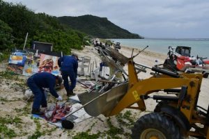 重機を使ってマリン事業者の占有物を撤去した＝20日、城辺の新城海岸