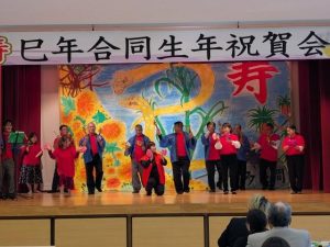 トゥイ会に参加し余興を披露する還暦の巳年生まれの皆さん＝17日、村コミュニティー施設