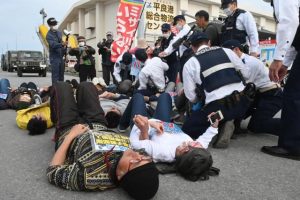 抗議のため路上に寝転び抵抗する参加者と排除する宮古島署の署員＝26日、平良港