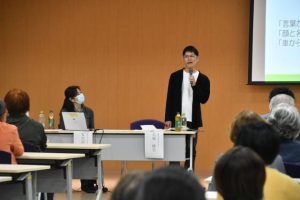 若年性認知症について講演する大城さん（右）＝23日、市役所大ホール