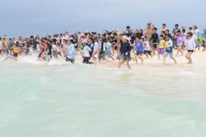 歓声を上げながら一斉に海に向かって走り出す子供たち＝与那覇前浜ビーチ（写真は昨年の海びらきの様子）