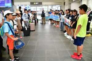 海・山体験交流宿泊研修会で来島した白川町の児童たち（左側）を横断幕で歓迎した下地小の児童たち＝22日、宮古空港