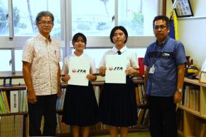 玉城支社長（左）から平良さん（中央左）、友利さん（同右）に宮古－那覇間の往復航空券が贈られた。右は松原校長＝18日、宮古高校