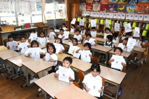 「よい子のあゆみ」を受け取り笑顔を見せる児童たち＝18日、平一小学校