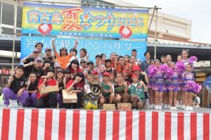 優勝盾を手にする「ＡＹＡＳＥ」（前列中央）、出場者、関係者の皆さん＝26日、市公設市場前特設ステージ