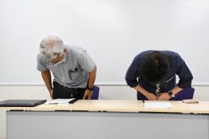 記者会見で深々と頭を下げる下地部長(右)と池間幸生建築課長=7日、市役所