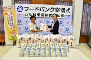 善平部長（右）が友利課長に米を手渡した＝21日、平良老人福祉センター