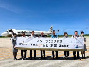 横断幕を手にスターラックス航空の下地島・台北運航開始を喜ぶ嘉数市長（左から４人目）ら関係者＝22日、下地島空港（提供）