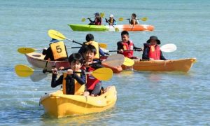 シーカヤック体験で息を合わせてこぐ児童たち＝９日、伊良部佐和田の浜