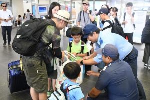 水難事故防止のトートバッグなどを配布する署員ら＝15日、宮古空港