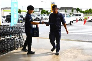 浄化槽の日をＰＲするパンフレットが入ったバッグを買い物客に手渡した＝27日、メイクマン宮古店